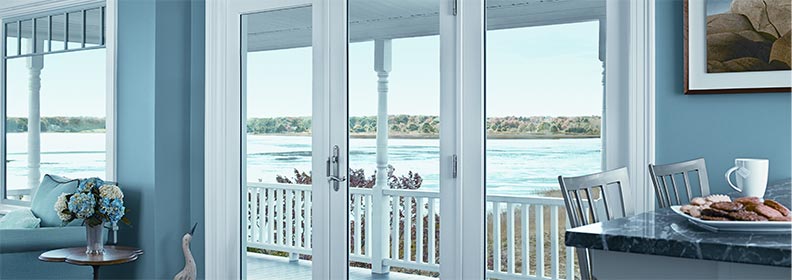 hinged french doors opening to a deck with view of a beach