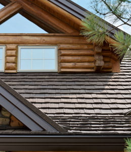 log building featuring detailing of dark brown stone-coated metal shake roofing