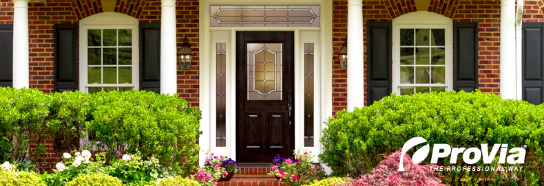 dark ProVia door with decorative glass on a grand brick house with white pillars and large green bushes