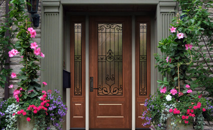 brown ProVia door with multiple decorative windows on stone house with flowering vines