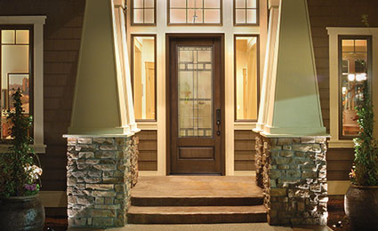 dark Therma-Tru door with wood appearance and large decorative window brightly lit at night