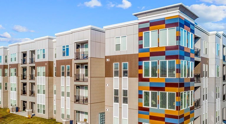 wide shot of apartments featuring light nichiha fiber cement siding contrasted with bright accent colors