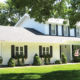 white home exterior with seamless steel siding, gray roofing, and many windows with dark shutters