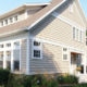 light tan home exterior with seamless steel siding, light brown roofing, and white detailing