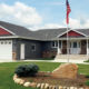 dark gray home exterior with seamless steel siding, matching roofing, dark red accents, and curated lawn