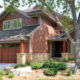brick-colored home exterior with seamless steel siding, matching shake accents, gray roofing, and large garage doors
