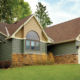 home exterior with subdued green seamless steel siding, brown roofing, tan shake accents, and orange-brown rock accents