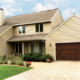 tan home exterior with seamless steel siding, light brown roofing, and dark brown garage door