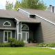 subdued-green home exterior with seamless steel siding, gray roofing, and white trim