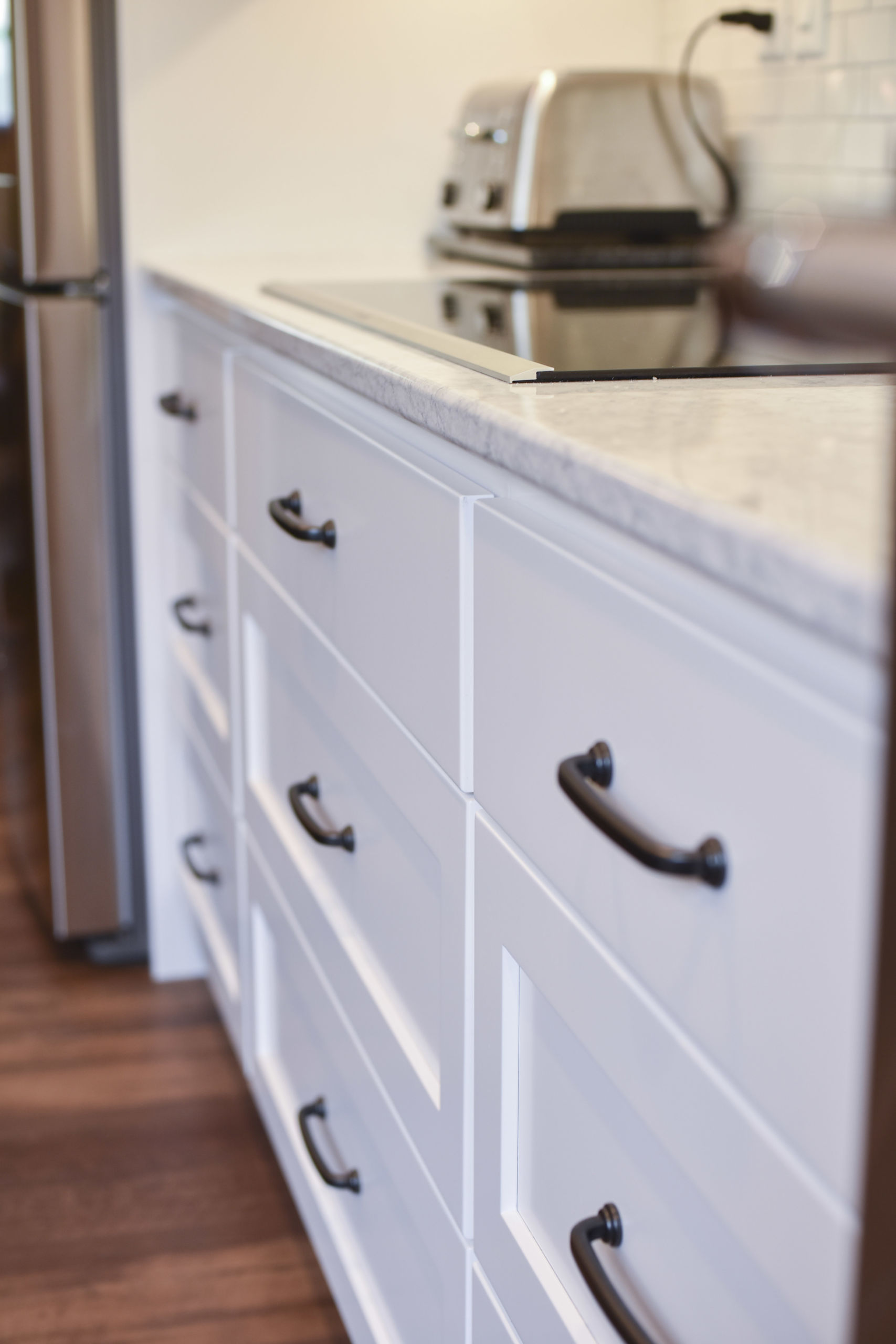 white painted kitchen drawers beneath a counter with a cooktop