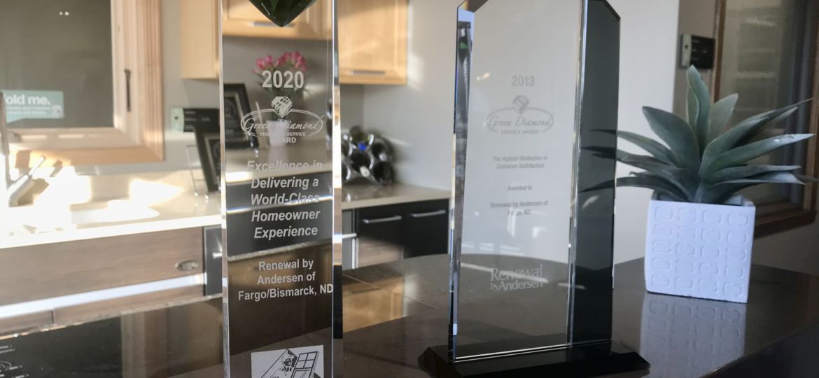 Two clear glass Green Diamond awards displayed on a countertop