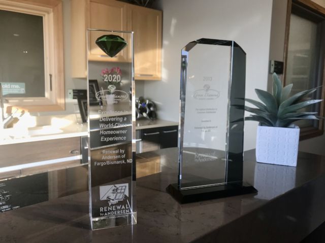 Two clear glass Green Diamond awards displayed on a countertop