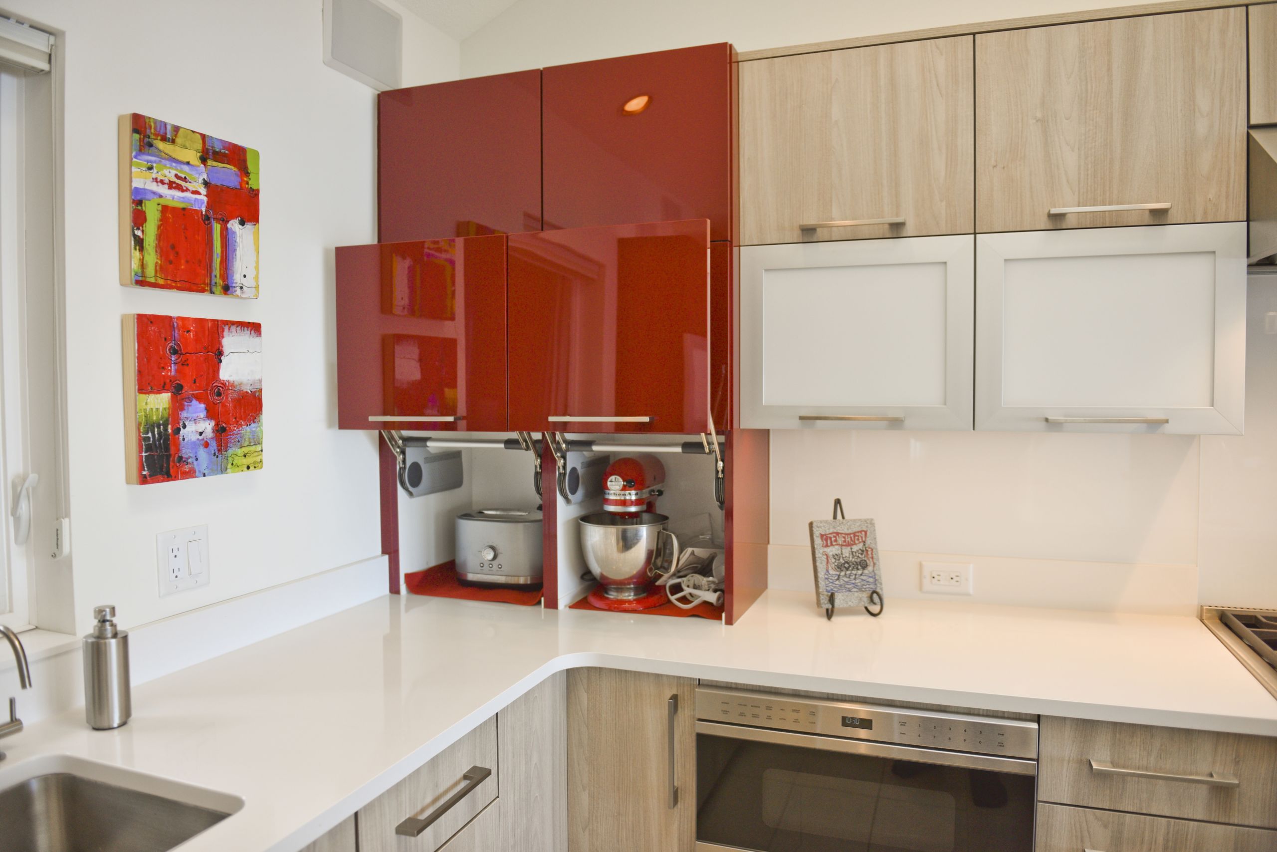 corner of a modern kitchen featuring red accent cabinets