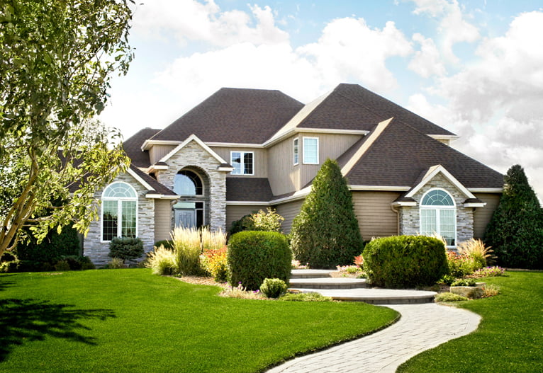 home exterior with tan siding, brown roofing, and stone accents