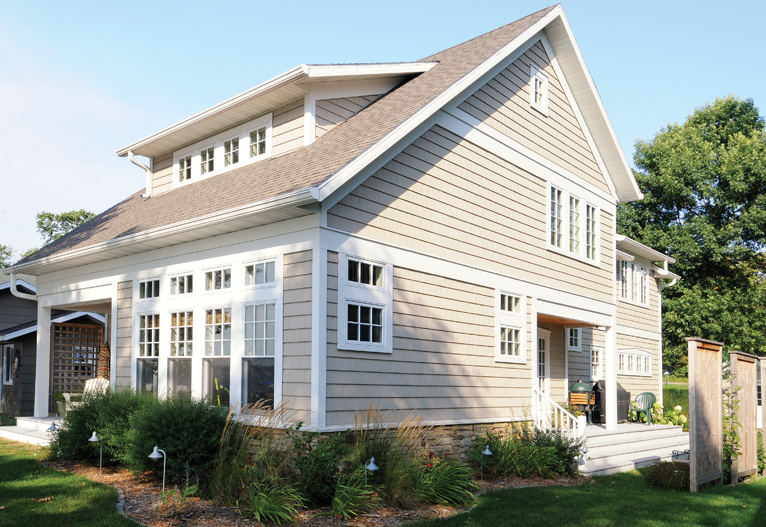 modern cottage home with light siding and many small windows with colonial grilles