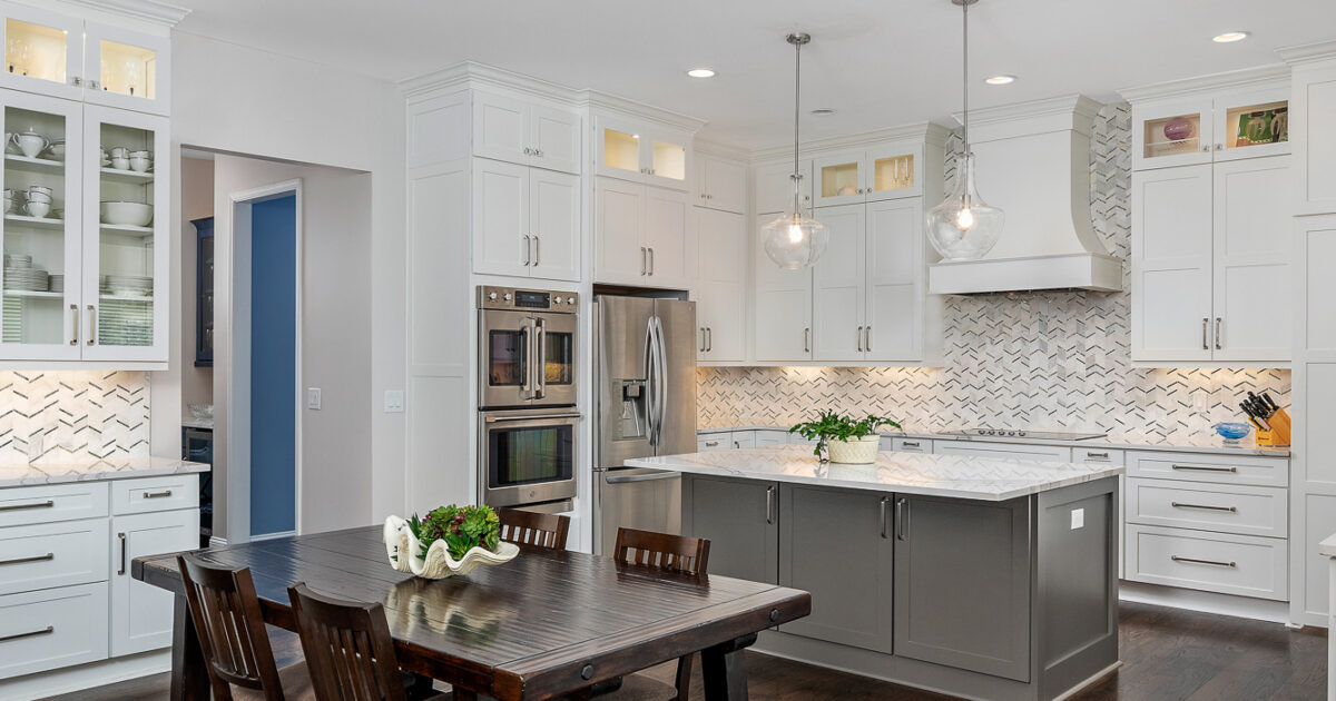 modern kitchen with white Showplace cabinets, wooden table, and stainless steel appliances